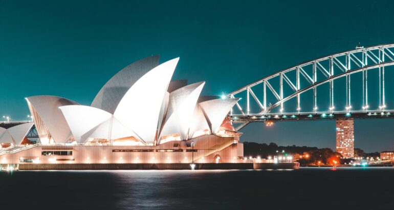 Stunning night view of Sydney Opera House and Harbour Bridge, beautifully illuminated against a clear sky.